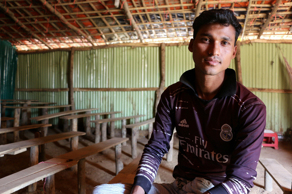 A man in a 'fly emirates' football shirt sits inside