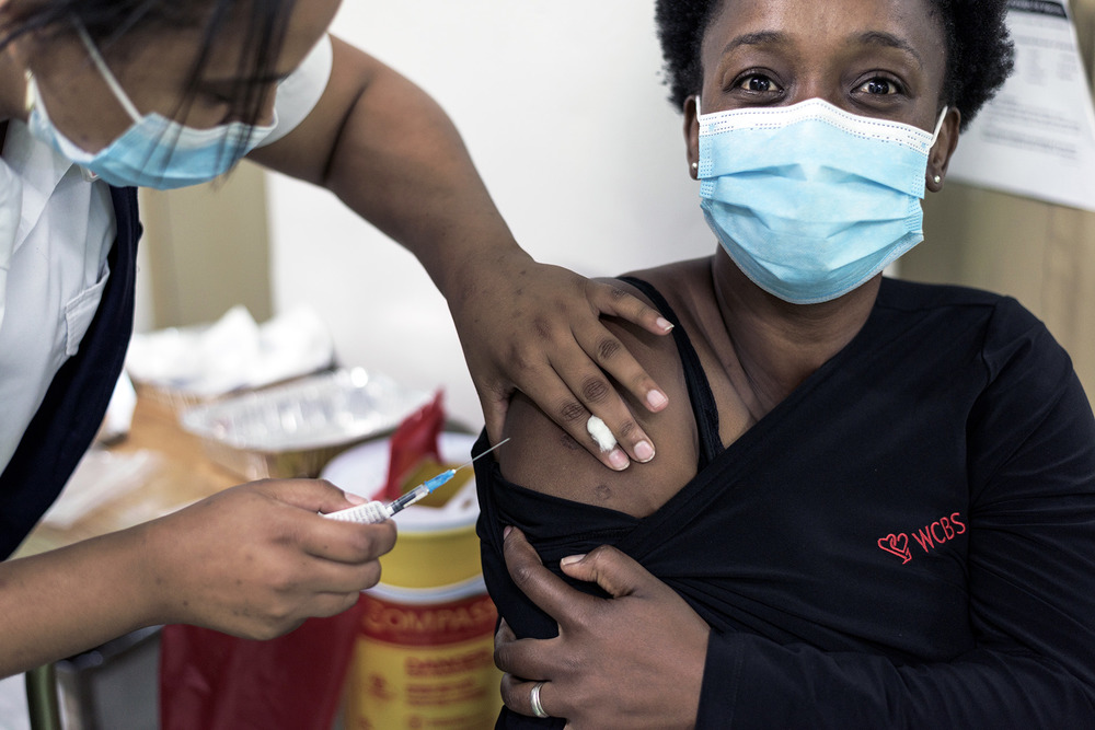 A woman wearing a mask receives a vaccine jab