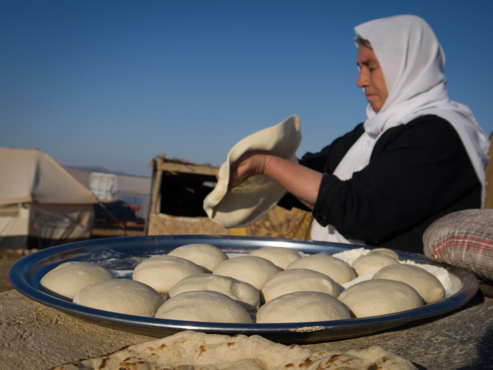 A Yazidi woman prepares bread dough on top of Mount Sinjar