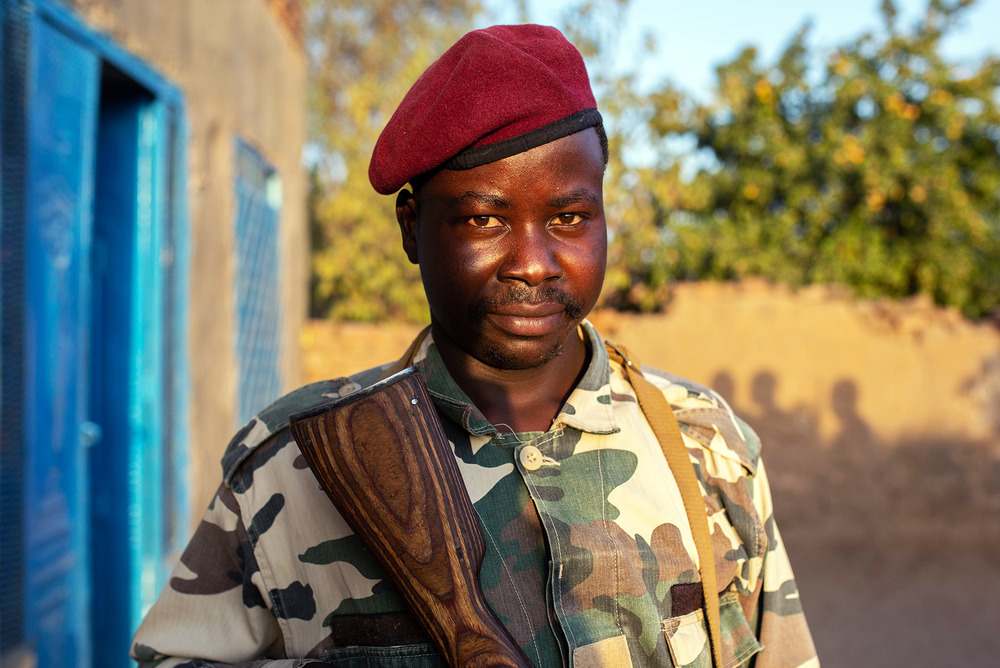A portrait of a guard belonging to the Sudan Liberation Movement-Transitional Council, who wears a red beret and holds a gun