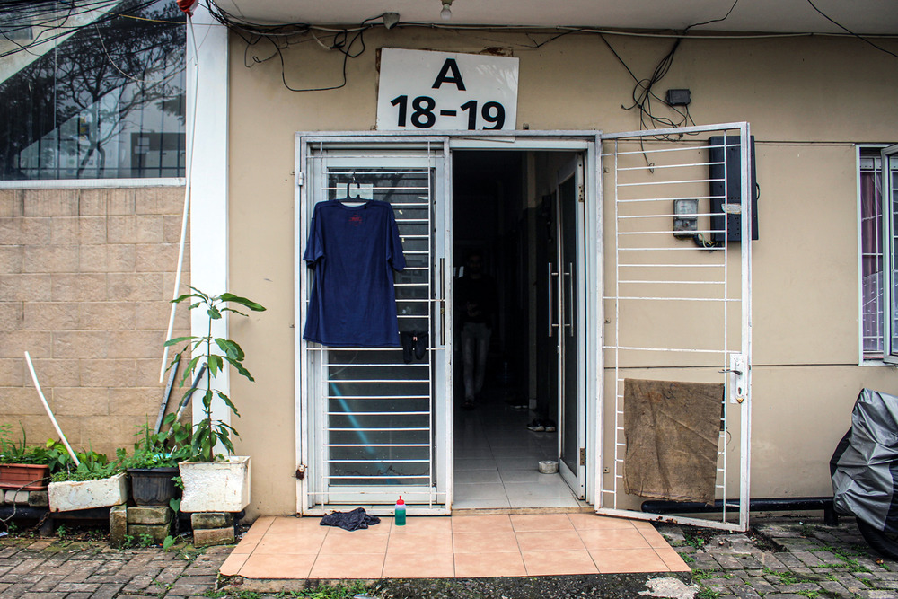 A shirt hangs on a clothes hanger outside the door of a small cement building