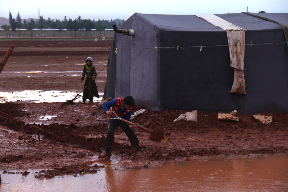 A child shovels water away from the tent he shares with his mother and sister in a makeshift displacement camp near Sarmada, north in December.