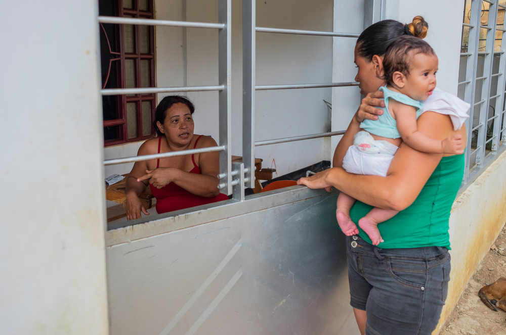 Marnellys Muentes (left) and her neighbour Élida Betancourt (right) speak through the railings of Muentes' house.