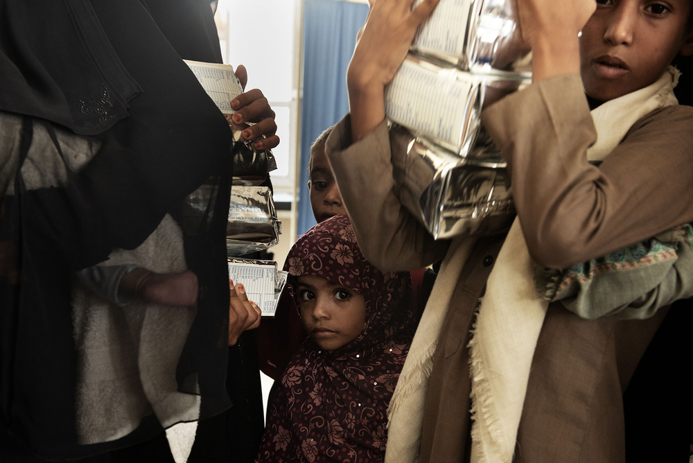 Yemenis pick up food aid at a medical centre in Abs district.