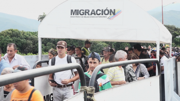 Venezuelans cross the border into Colombia under a sign that reads