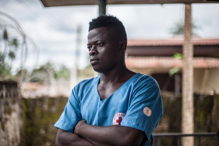 A portrait of a burial worker in Sierra Leone dressed in blue scrubs.