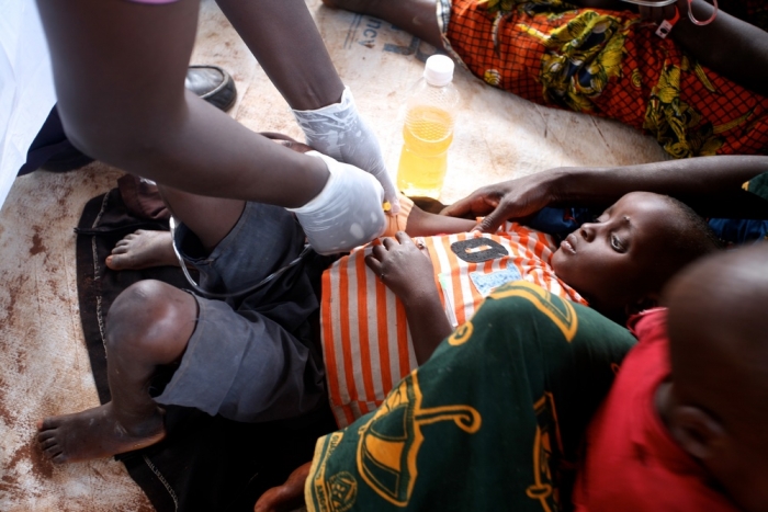 A Burundian refugee suspected of having cholera receives IV rehydration in the health clinic at Lake Tanganyika Stadium in Kigoma, Tanzania.