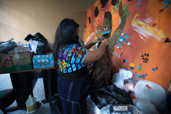 A member of the Tz'ununija' Indigenous Women's Movement sorts through clothing donations for people affected by Eta dropped off at the group's office in Guatemala City