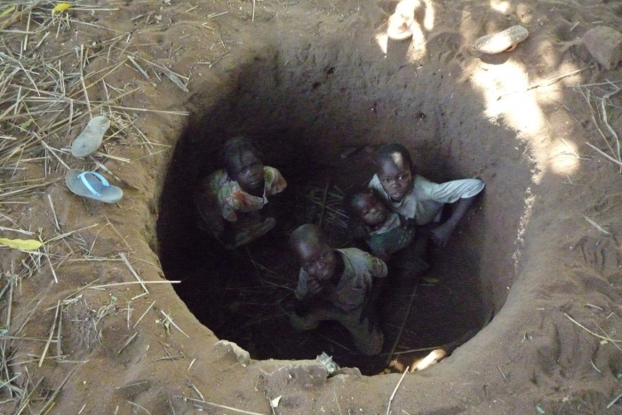 Nuba children shelter in a foxhole at the first sound of an Antonov bomber passing overhead