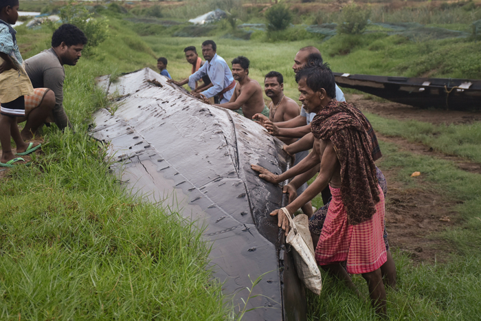 Photo of fishermen overturning a boat in a canal in India after Cyclone Fani.