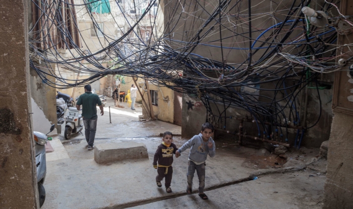 Two children walk under a nest of loose wires in the Bourj el-Barajneh neighborhood of Beirut.