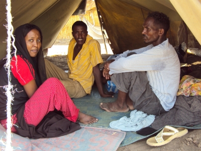 Shagarab Camp - Turmesgy Gabr Selassie (right) fled the Eritrean army 3 months ago. He shares this tent with 11 other men and women where they sleep on the ground. The only luxury in their tent is the thin sheets with which they cover themselves