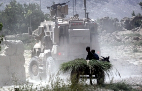 Children aboard a farm cart watch as American armored vehicles pass through a dirt road near a pomegranate orchard in Arghandab Valley, southern Afghanistan