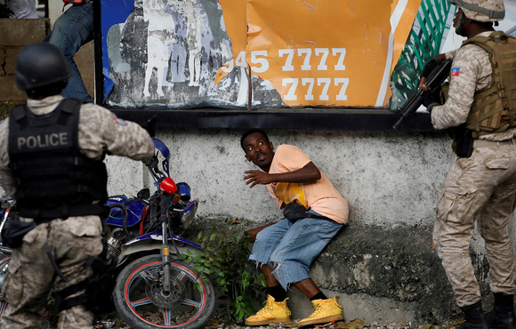 Haitian police officers confront a man during clashes with protesters marching the streets of the capital, Port-au-Prince, to demand the resignation of President Jovenel Moïse.