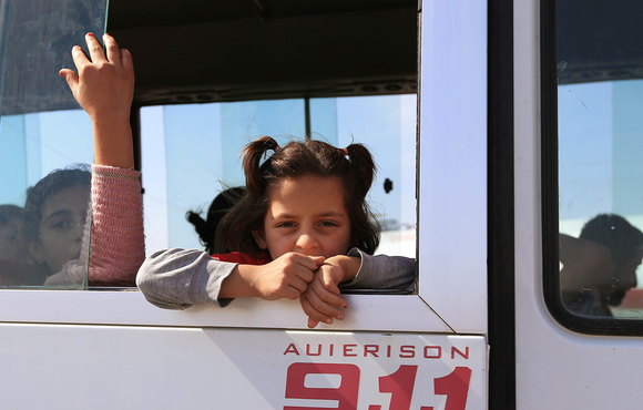 A Syrian child who fled violence with her family after the recent Turkish offensive is taken by bus to a displacement camp near Dohuk in northern Iraq. 