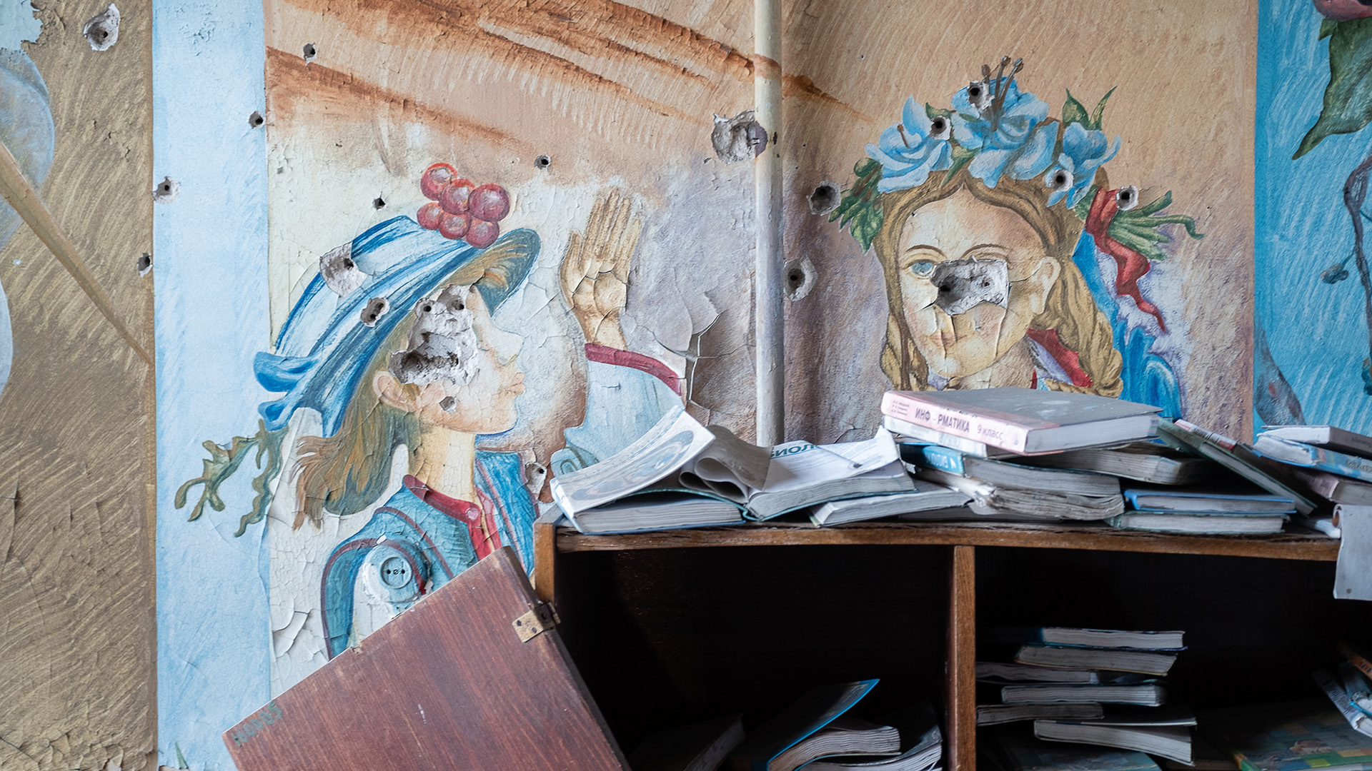 A school library in the village of Opytne. Soldiers have been training on the paintings of the children, leaving their faces marked with bullet holes.