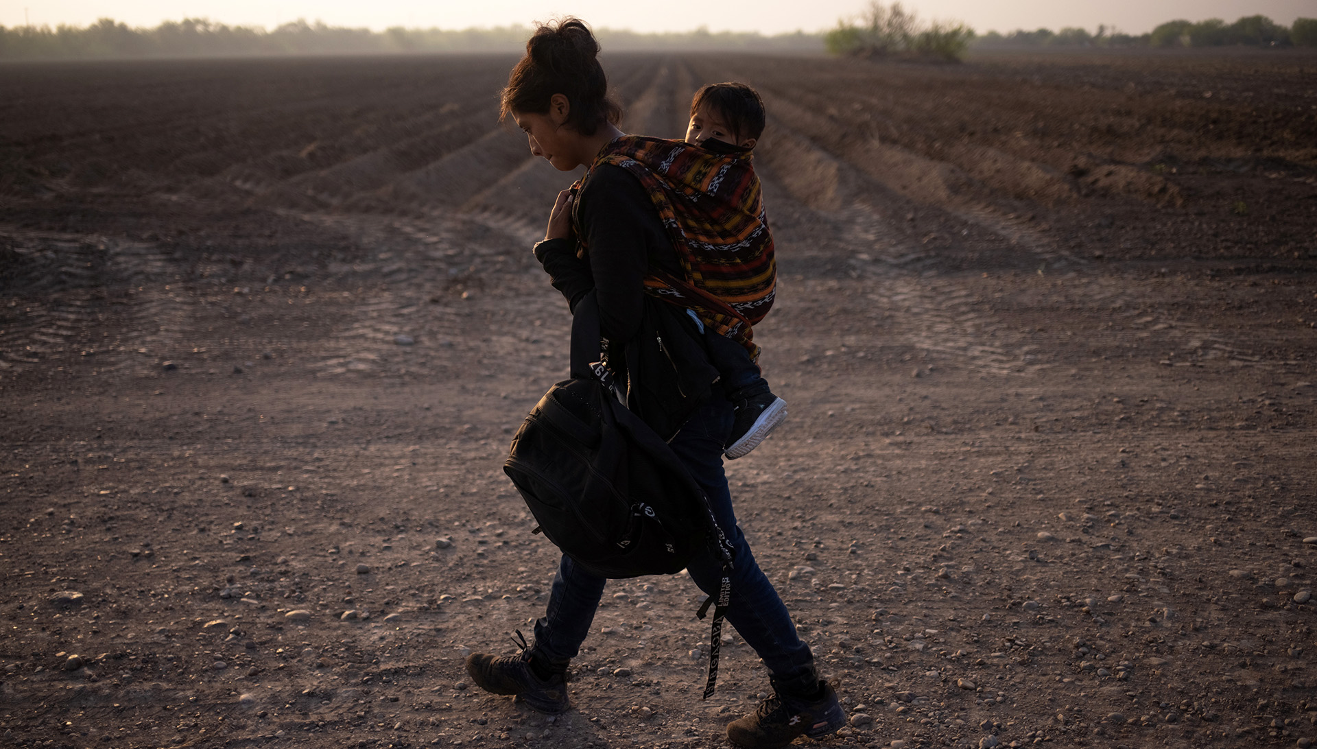 Mayra, a 17-year-old asylum seeking mother from Guatemala, carries her 13-month-old son Marvin after they crossed the Rio Grande river into the United States from Mexico on a raft, 17 March 2021.