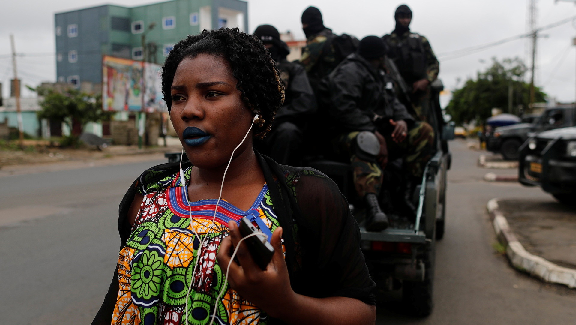 A woman walks past Cameroonian elite Rapid Intervention Battalion (BIR) members as they sit on their military vehicle during their patrol in the city of Buea in the anglophone southwest region, Cameroon, 4 October 2018