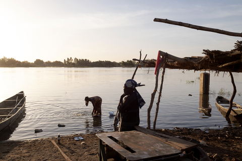 A scene at the water's edge with boats and a low lying sun