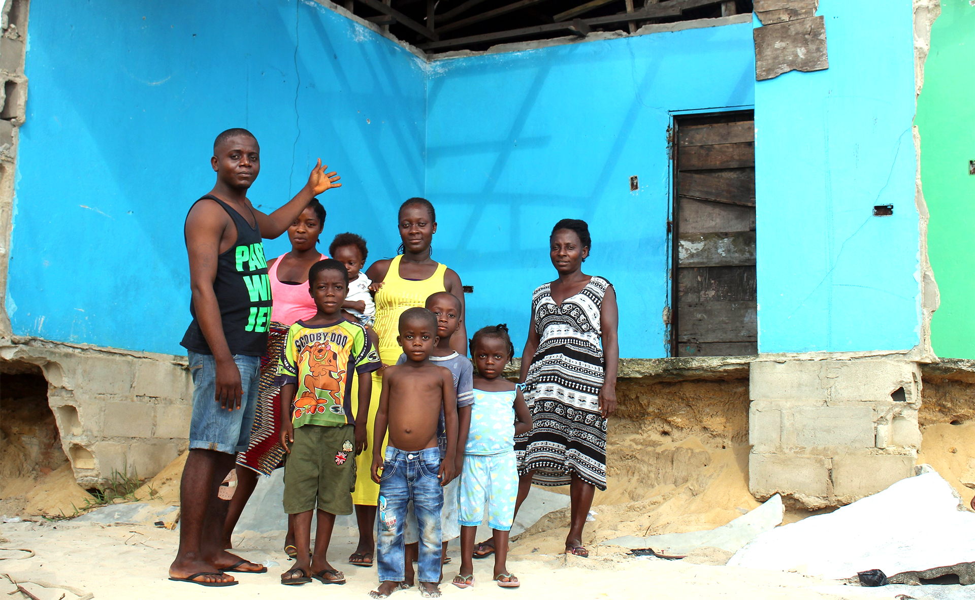 Lawrence Saweh stands with his family by what’s left of their home in the Liberian capital, Monrovia. A family in front of a broken building