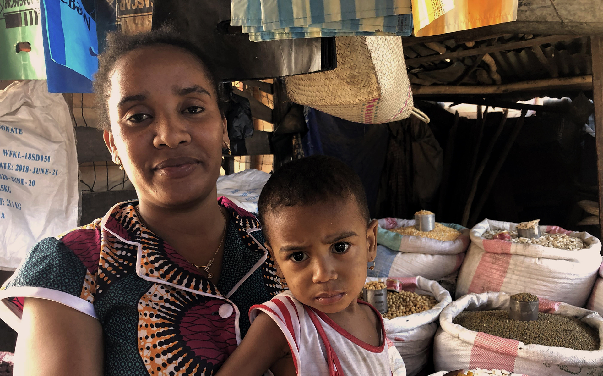 Like many traders in this market in Morondava, Alatsoa migrated from Madagascar’s drought-hit southern region. Woman and child in front of a food market stall