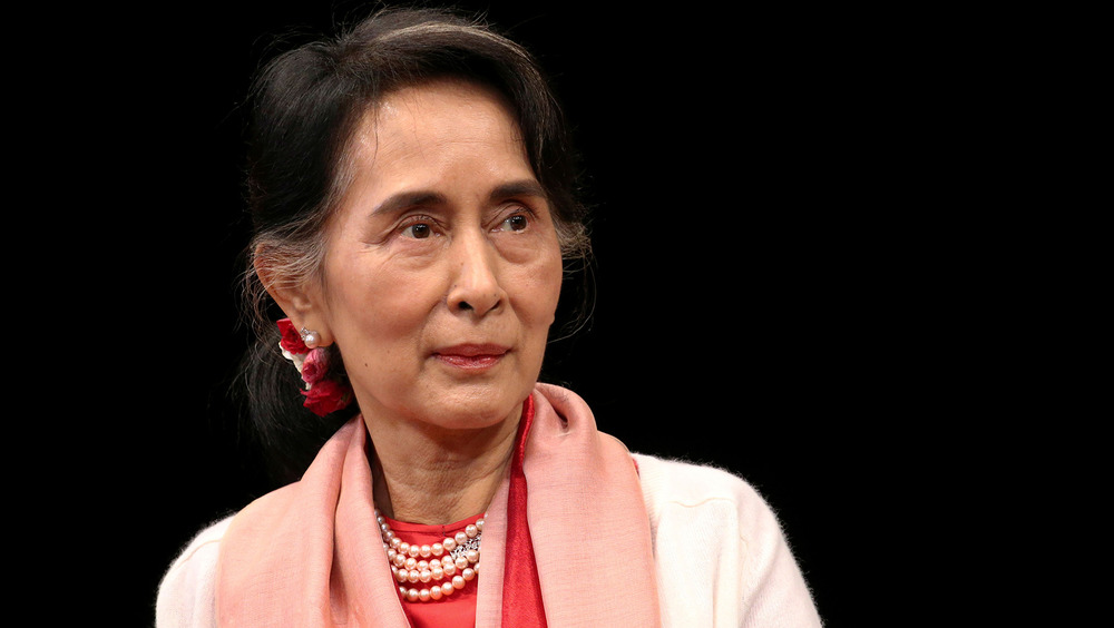 a portrait image of aung san suu kyi against a black backdrop.