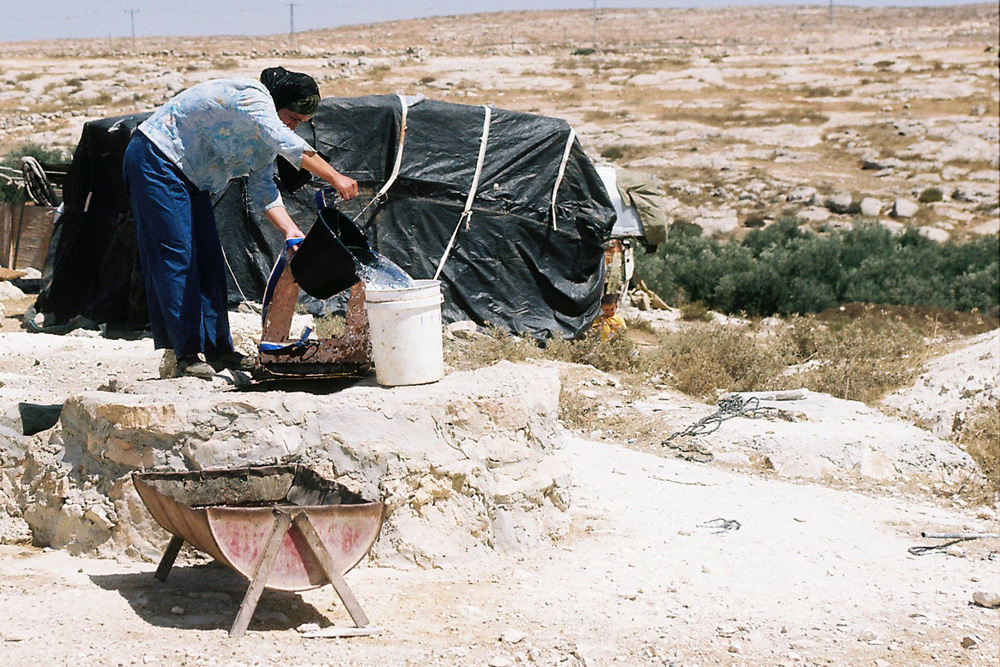 A Palestinian woman in Susya draws water from a cistern. Access to underground wells is restricted and in the summertime water becomes a precious commodity.