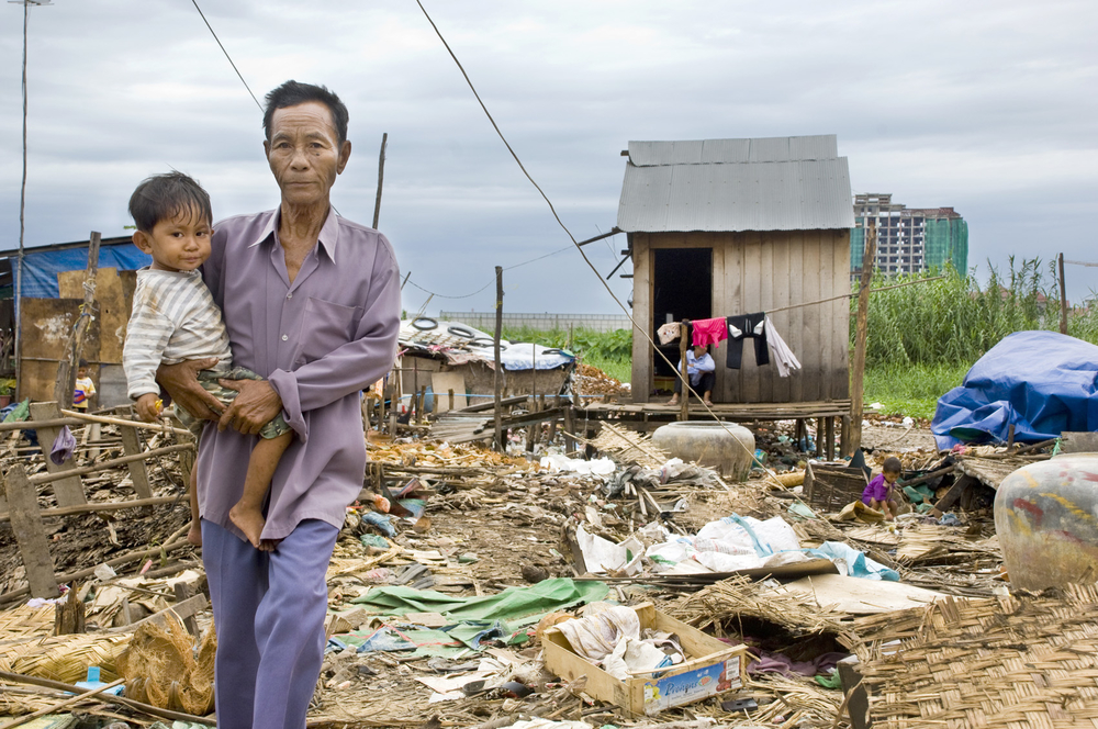 A man holds his child as he walks through the remains of a community known as Group 78 in central Phnom Penh on 16 July, 2009, a day before their forced eviction. Residents claimed they have been at location since 1983, giving them land rights, but govern