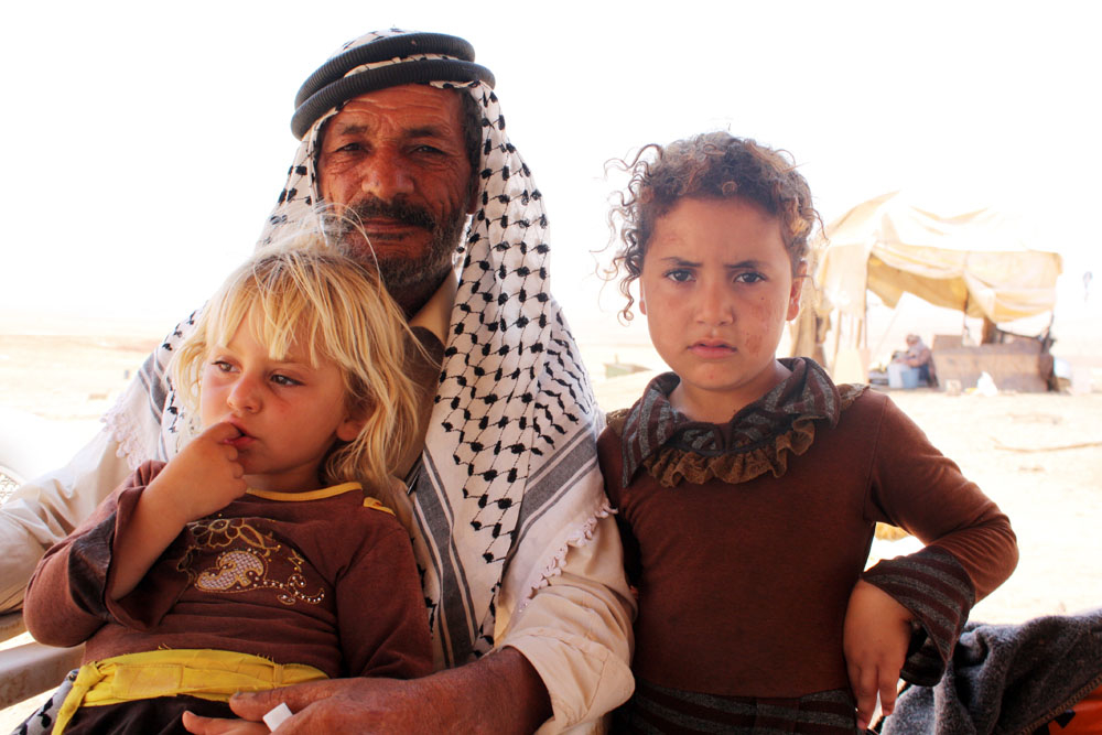 Shepherd Abdul Rahim Bsharat, 59, holds his two youngest daughters, Samoud, three (blonde) and Assia, five. The Bsharat family have lived and farmed in al-Hadidiya village in the West bank since the 1960s