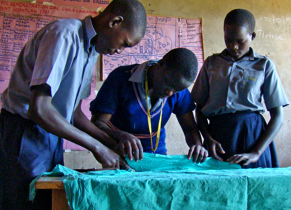 Pupils take measurements of a cotton cloth to be used to make sanitary pads in Uganda