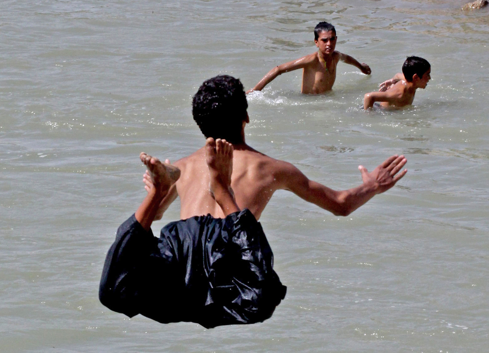 Children and young men swim in an irrigation canal in Arghandab Valley in southern Afghanistan