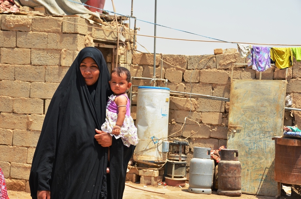A displaced woman holds her baby at a makeshift settlement, Al-Rustumiiya, on the outskirts of the Iraqi capital Baghdad. Squatters here lack proper electricity, water and sanitation and are at constant risk of eviction