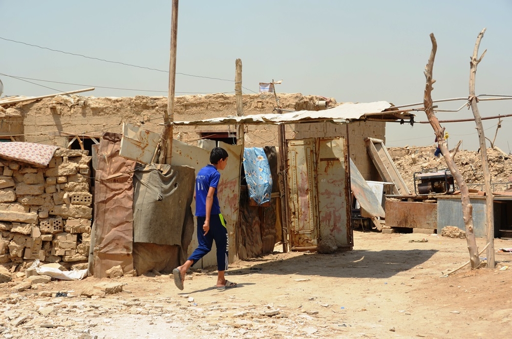 A boy walks past makeshift homes in Al-Rustumiya, an informal settlement for displaced people settlement on the outskirts of the Iraqi capital Baghdad