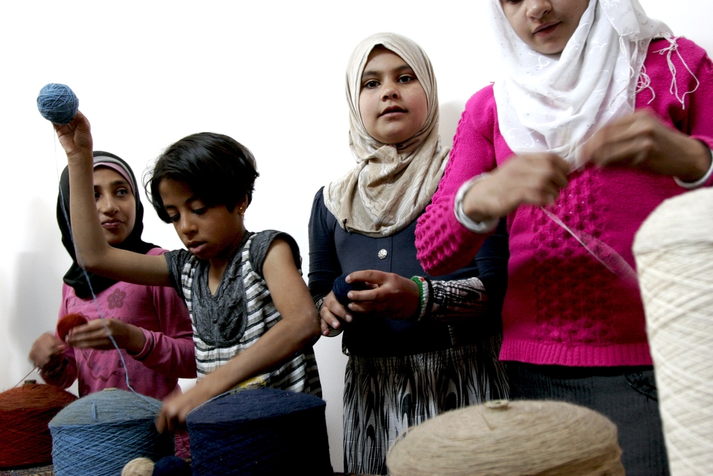 Syrian girls spool yarn for weaving into rugs in a women's-only space at Nizip Camp for Syrian refugees in southern Turkey