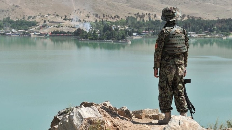 An Afghan National Army (ANA) soldier looks on from a hill near the Spozhmai Hotel following an attack by Taliban militants at Qargha lake on the outskirts of Kabul on June 22, 2012