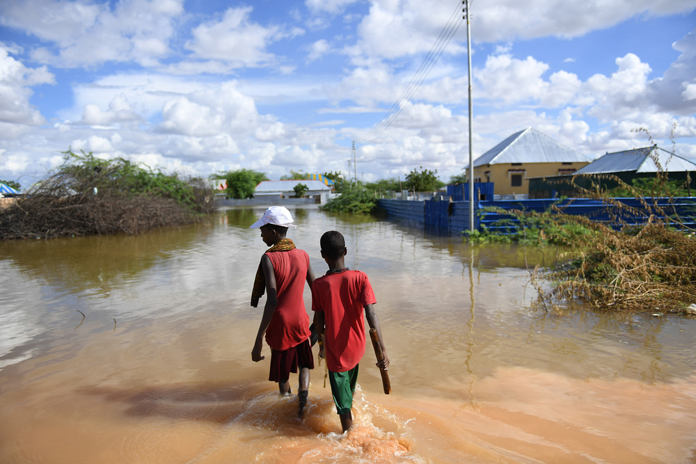 boys walk through   flooded area in belet weyne, somalia, in
