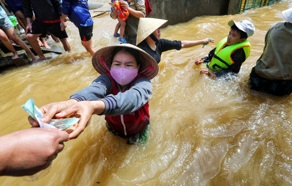 A resident gets money from a volunteer at a flooded area in Quang Binh province, Vietnam, on 23 October 2020.