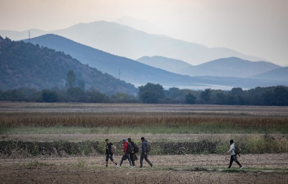 A group of asylum seekers and migrants walking in Greece, with the North Macedonian Mountains in the background. Overland travel from Serbia and through North Macedonia is a common route for Cubans hoping to reach the EU. 