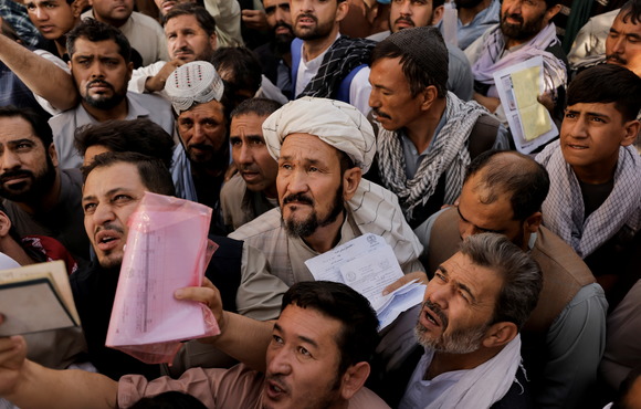 Afghans gather outside the passport office in Kabul after Taliban officials announce they will start issuing passports  again, in October 2021.