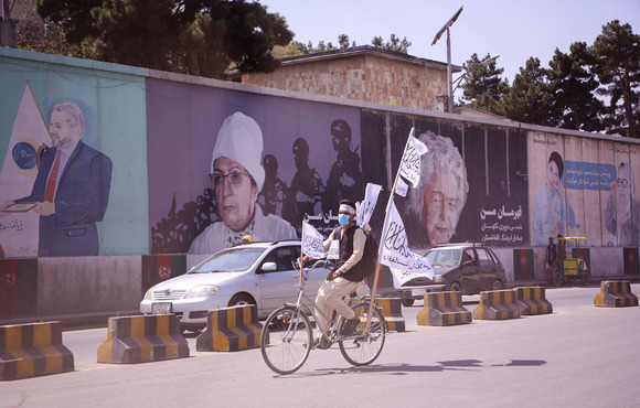An Afghan man rides a bicycle carrying Taliban flags through the streets of the capital, Kabul, on 2 September 2021.