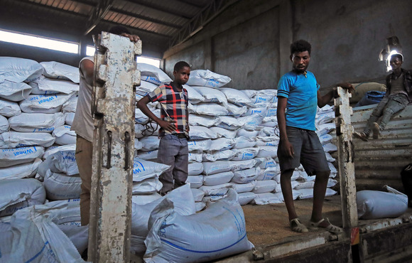 Ethiopian porters unload food aid bound for victims of war after a checkpoint leading to Tigray in Mai Tsebri town, Ethiopia, 26 June 2021.