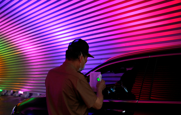 A staff member holds a thermometer for temperature checks as he requires people to scan a health code at the entrance of the Maple Garden Drive-in Cinema, during Beijing International Film Festival following the coronavirus disease (COVID-19) outbreak, in