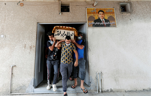 Several men carry a coffin through a doorway. 
