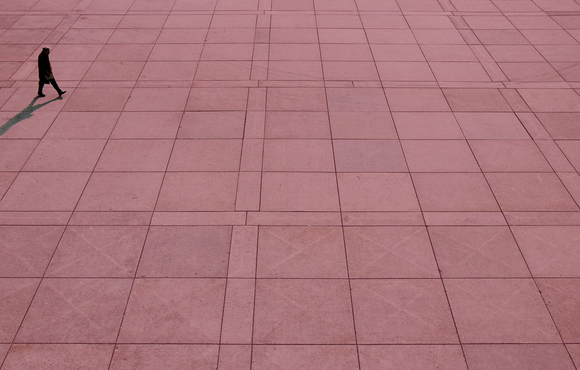 Man walking across open concrete space