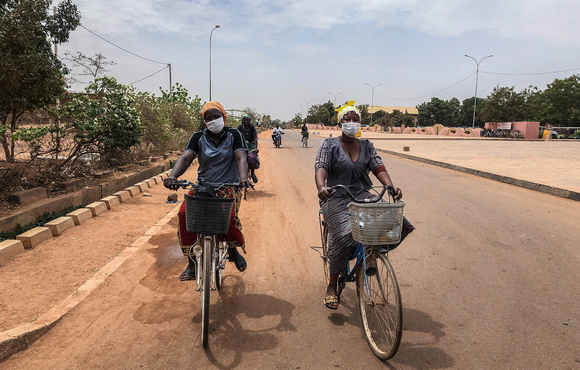 Ouagadougou residents wear masks while cycling
