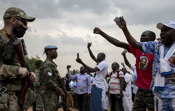 Soldiers and civilians yell at each other from either side of the frame.