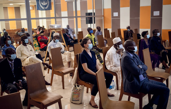 The photo shows a scattered crowd of people sitting in chairs watching the screening, which is out of view. 