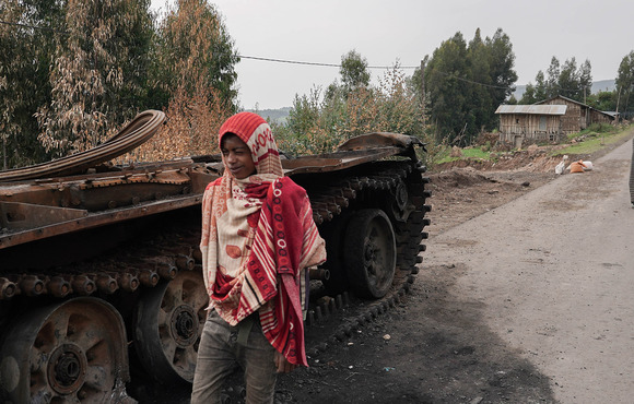 Residents walk past an abandoned tank on a main road in Amhara region, where hundreds of thousands of people have fled recent fighting.