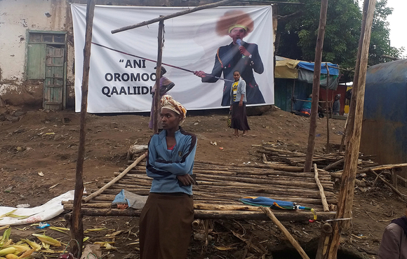 People walk past a poster of slain Ethiopian singer Hachalu Hundessa