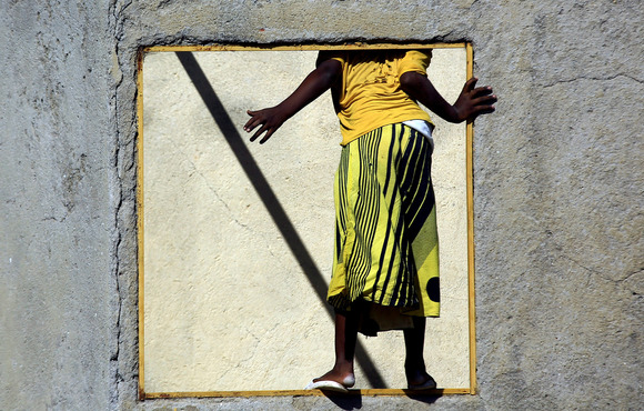 An Ethiopian refugee who fled the country's Tigray region into Sudan, stands with their back facing the camera, looking through an empty window.  